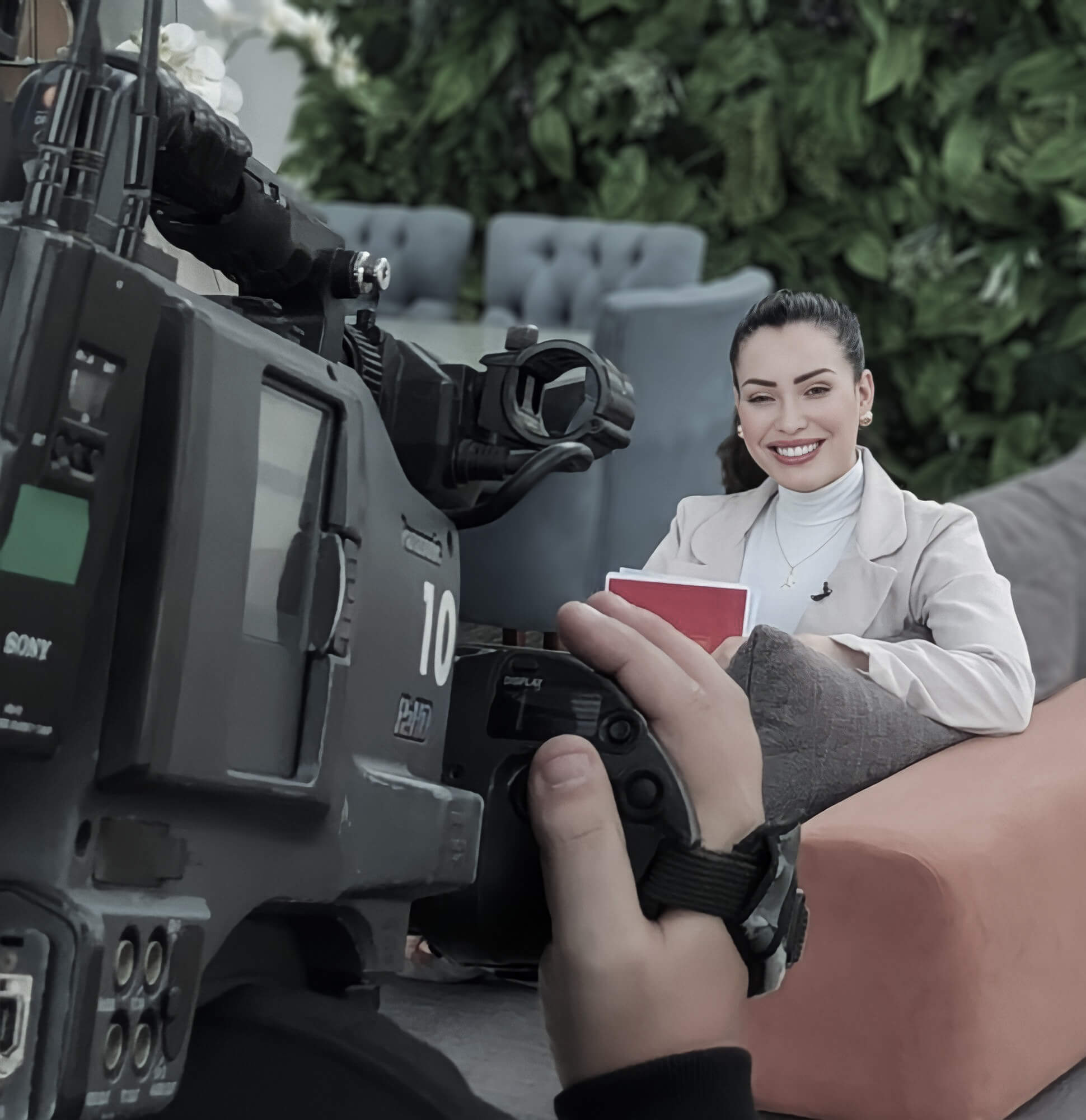 Luma Vidal gravando para TV, sentada em uma poltrona.